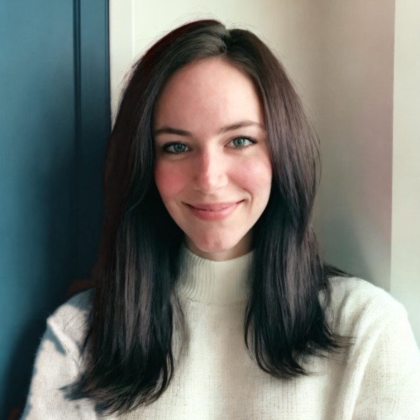 Tali, smiling, with long dark hair and a cream sweater